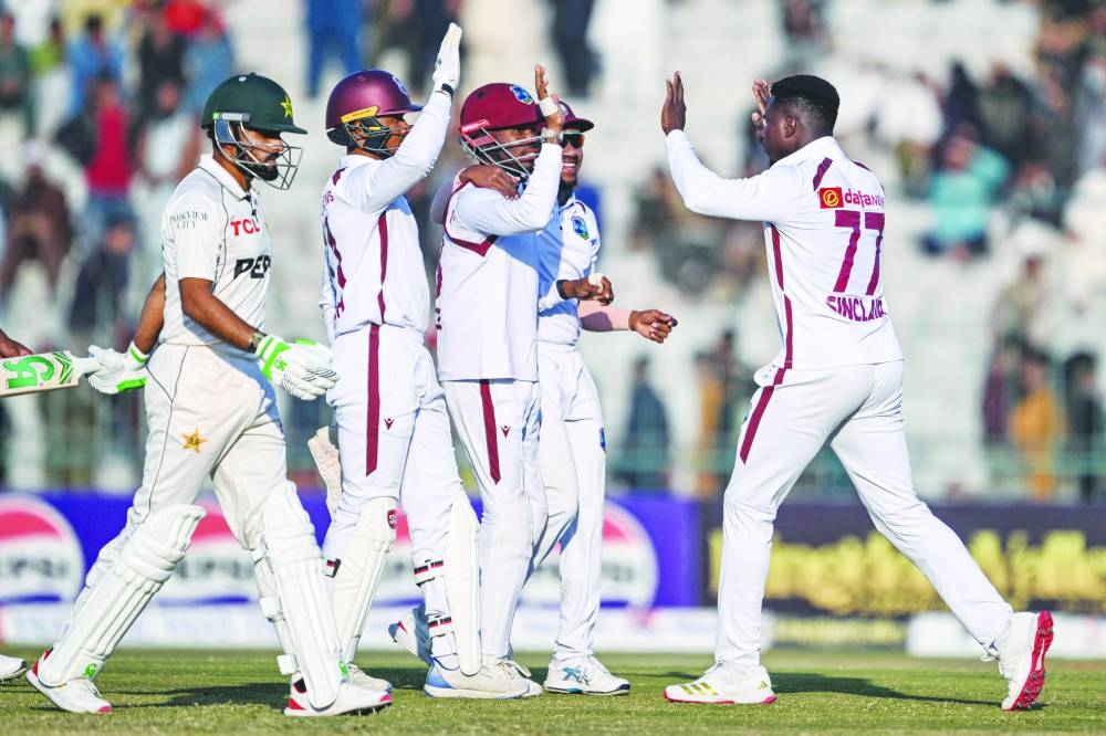 
West Indies’ Kevin Sinclair (right) celebrates with his teammates after taking the wicket of Pakistan’s Babar Azam (left) during the second day of the second Test at the Multan Cricket Stadium in Multan yesterday. (AFP) 