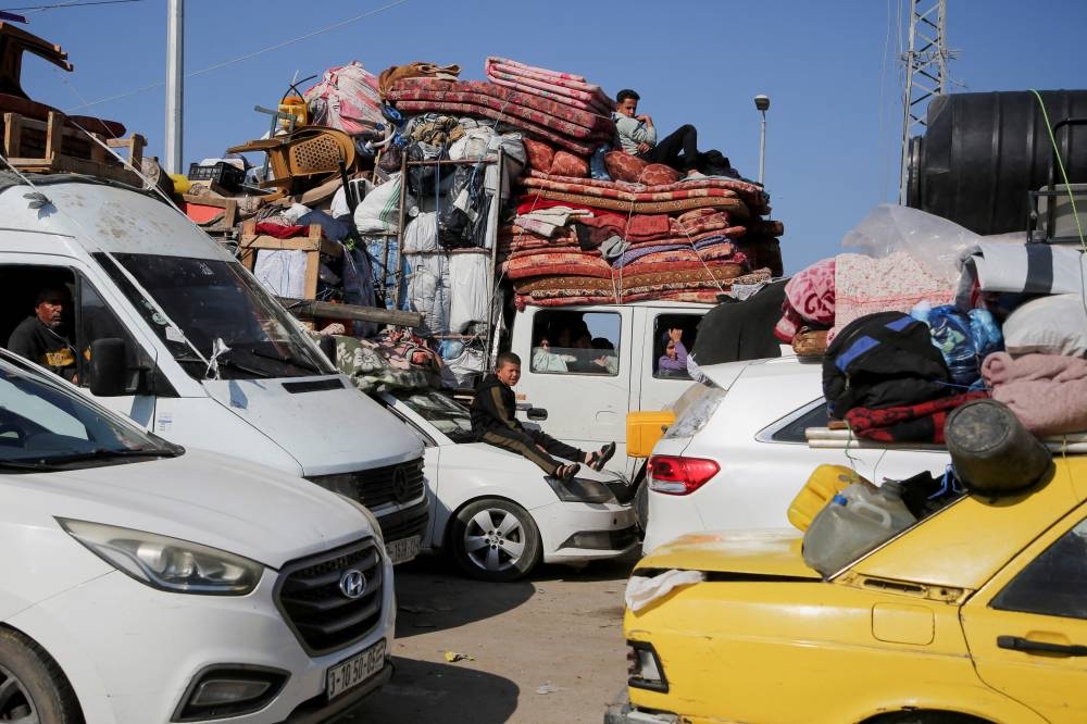 Palestinians, who were displaced to the south at Israel's order during the war, wait to head back to their homes in northern Gaza by vehicle through Salahudeen Road, in the central Gaza Strip, on Monday. REUTERS