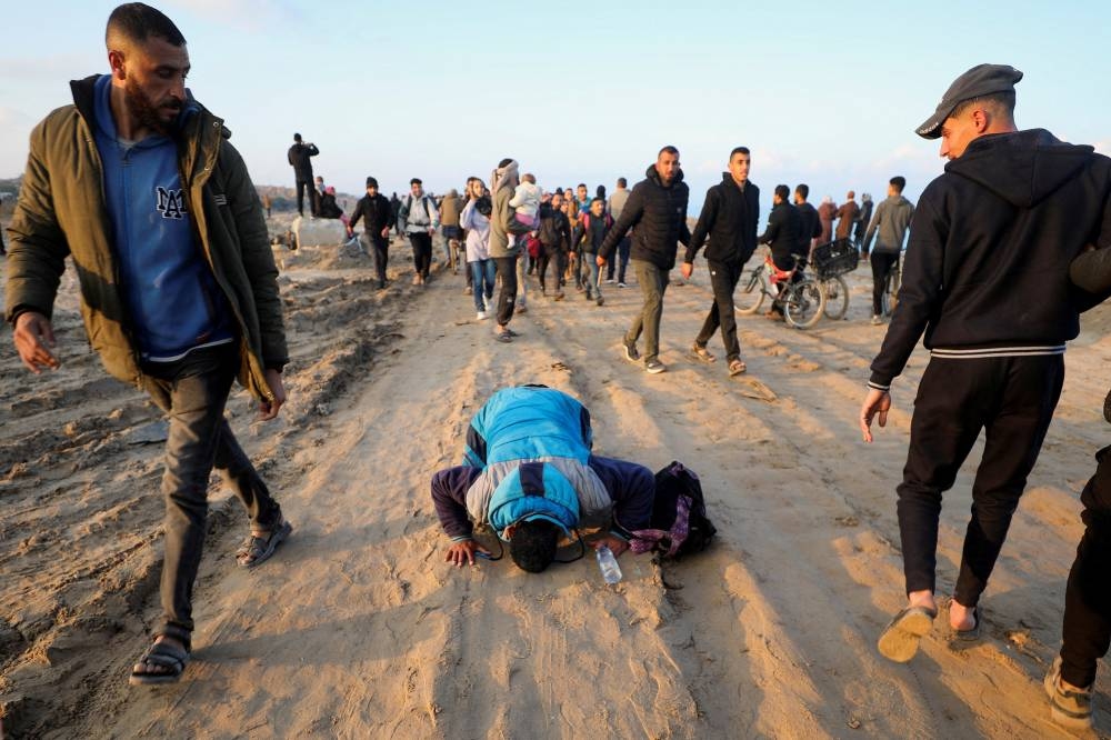 A man prays as Palestinians, who were displaced to the south at Israel's order during the war, make their way as they return to their homes in the northern Gaza, in Gaza City, on Monday. REUTERS