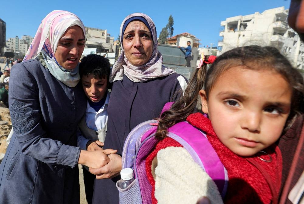 Palestinian woman Umm Ali holds the hand of her daughter, Souad Atallah, who was displaced to the south at Israel's order during the war, upon her return to northern Gaza, in Gaza City, on Monday. REUTERS