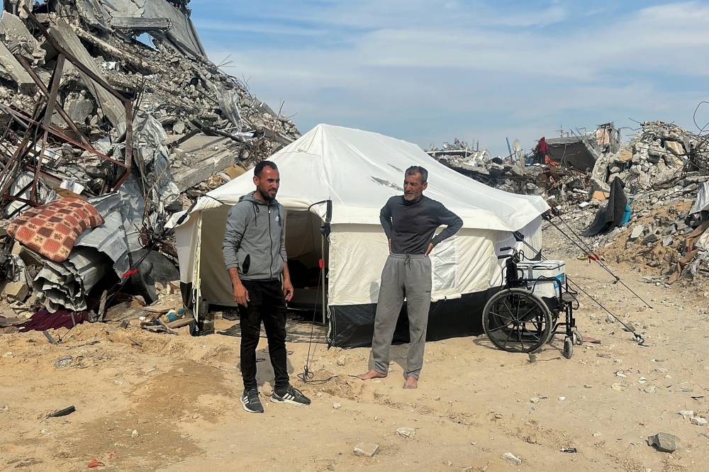 Palestinian Younis Al-Err (L), who was displaced at Israel's order during the war, stands near rubble of his house after returning to Jabalia refugee camp, in the northern Gaza Strip, on Tuesday. REUTERS