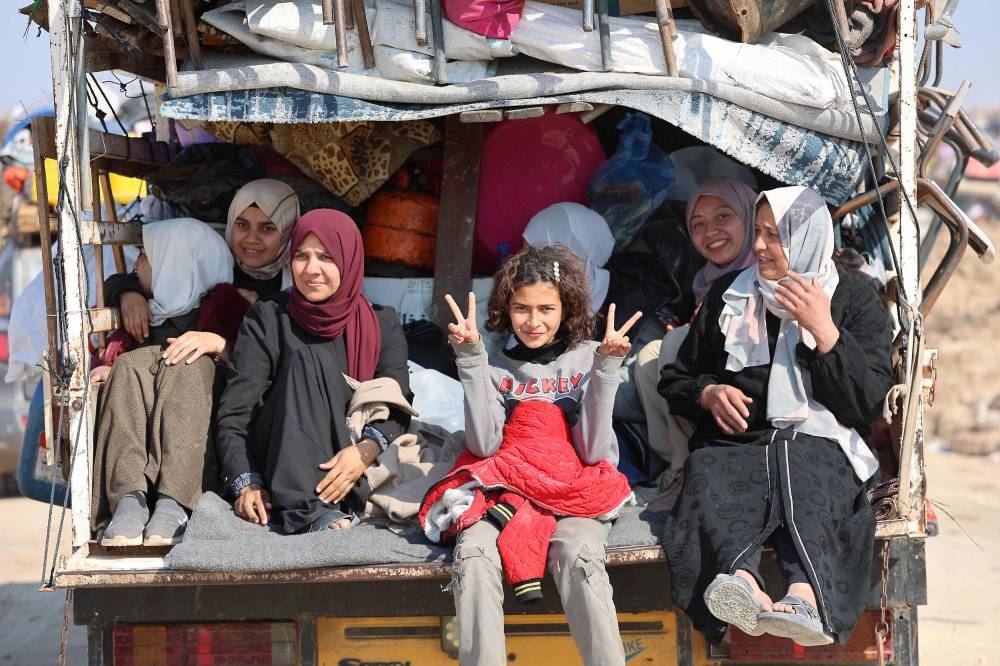 Displaced Palestinian children and a woman sit in the back of a truck as people make their way from the south to the northern parts of the Gaza Strip, on Salah al-Din road in central Gaza, on Wednesday. AFP