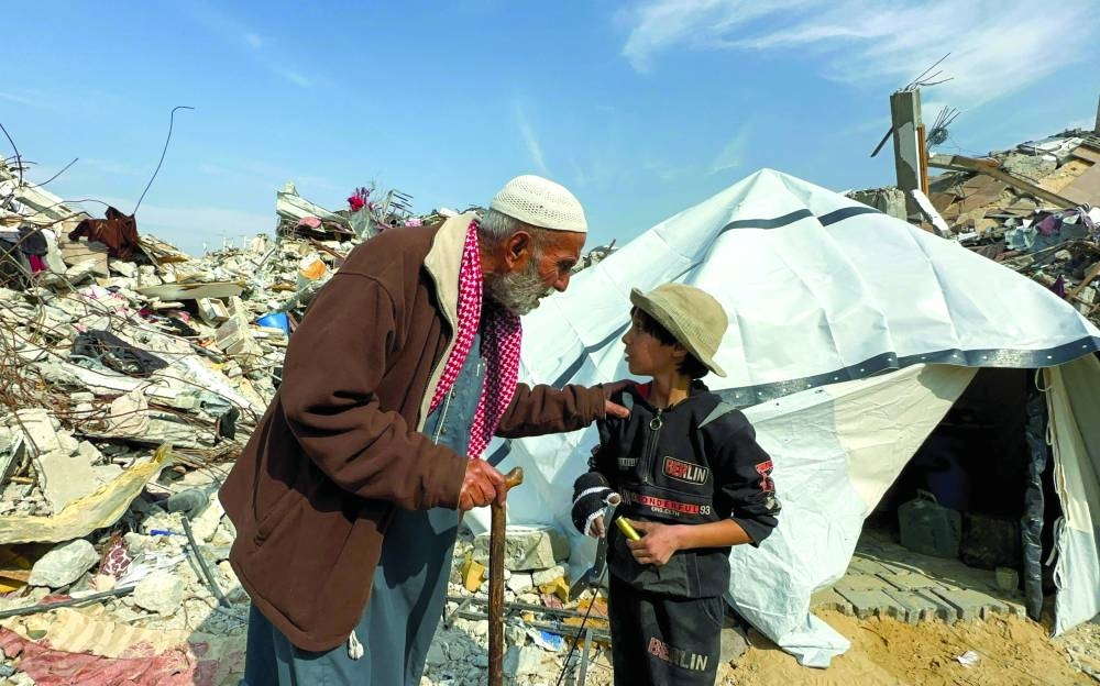 
A Palestinian man, who was displaced at Israel’s order during the war, speaks with a child after returning to his destroyed house, amid a ceasefire between Israel and Hamas, in Jabalia refugee camp in the northern Gaza Strip. 