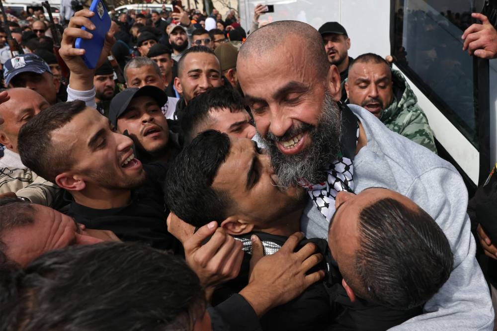 A former Palestinian prisoner released by Israel is hugged by members of his family as he disembarks a Red Cross bus after arriving in Ramallah, in the occupied West Bank on Saturday. AFP