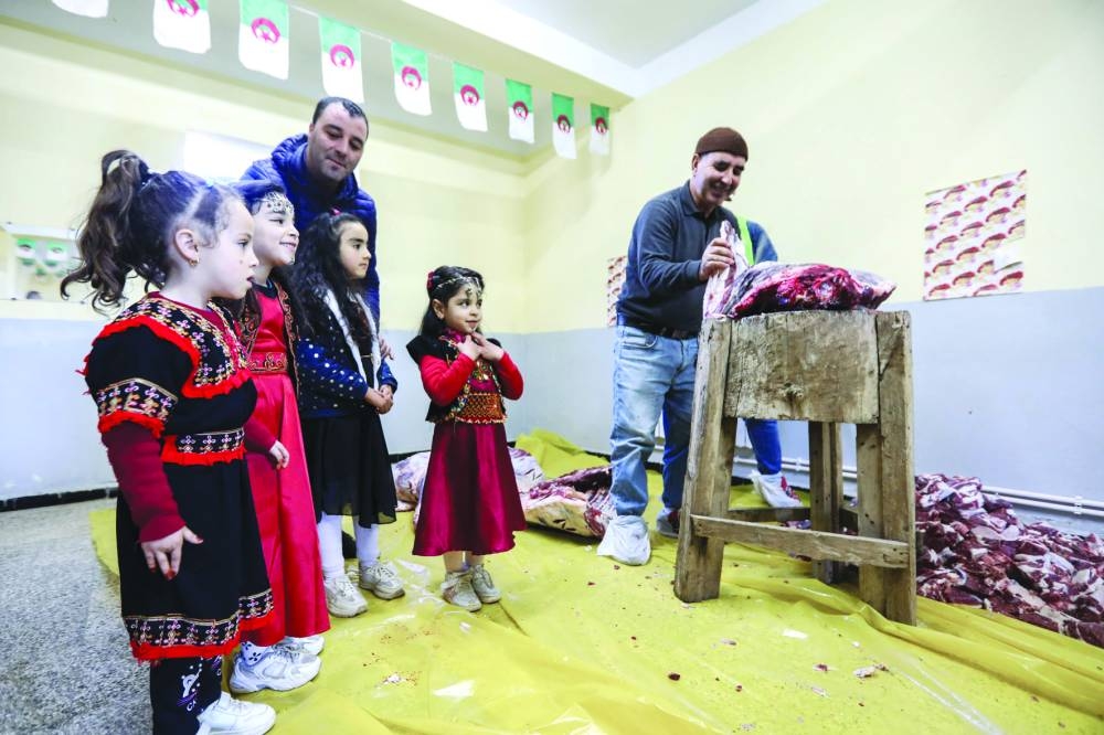 
Children dressed in traditional outfits watch as men prepare portions of meat as part of Algeria’s Tamechrit, based on the Amazigh New Year’s traditions, in Bajaia. 