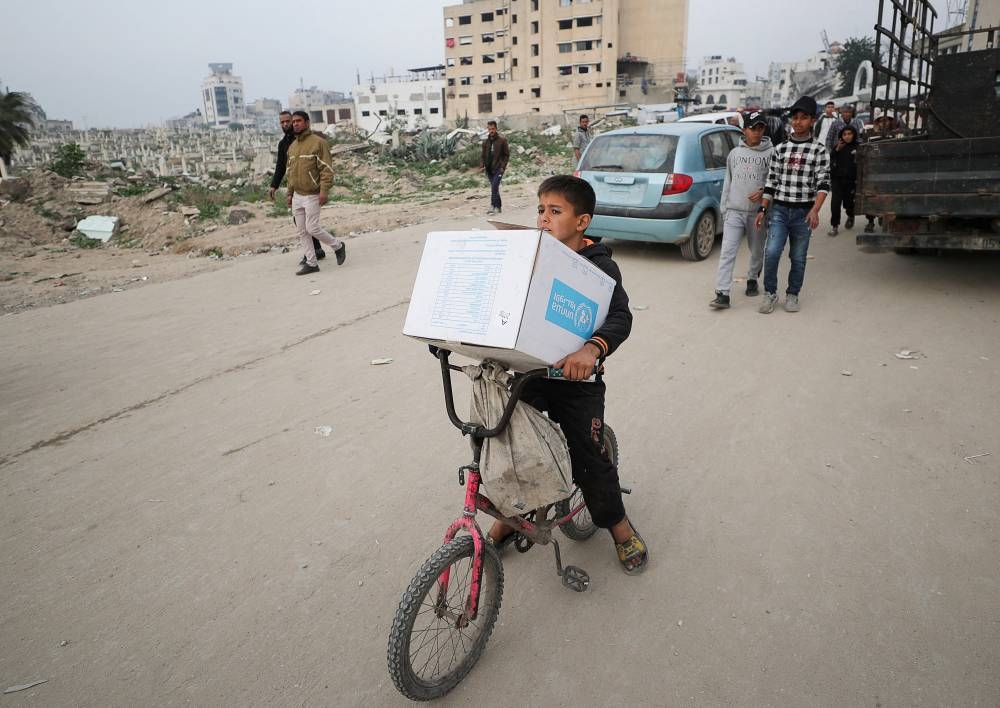 A Palestinian boy carries an aid box provided by UNRWA, in Gaza City, on Monday. REUTERS