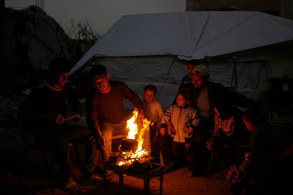 Palestinian twins Mahmoud and Ibrahim Al-Atout, who were separated during the war, make tea on a fire near the rubble of their destroyed house after being reunited, in Jabalia, northern Gaza Strip.