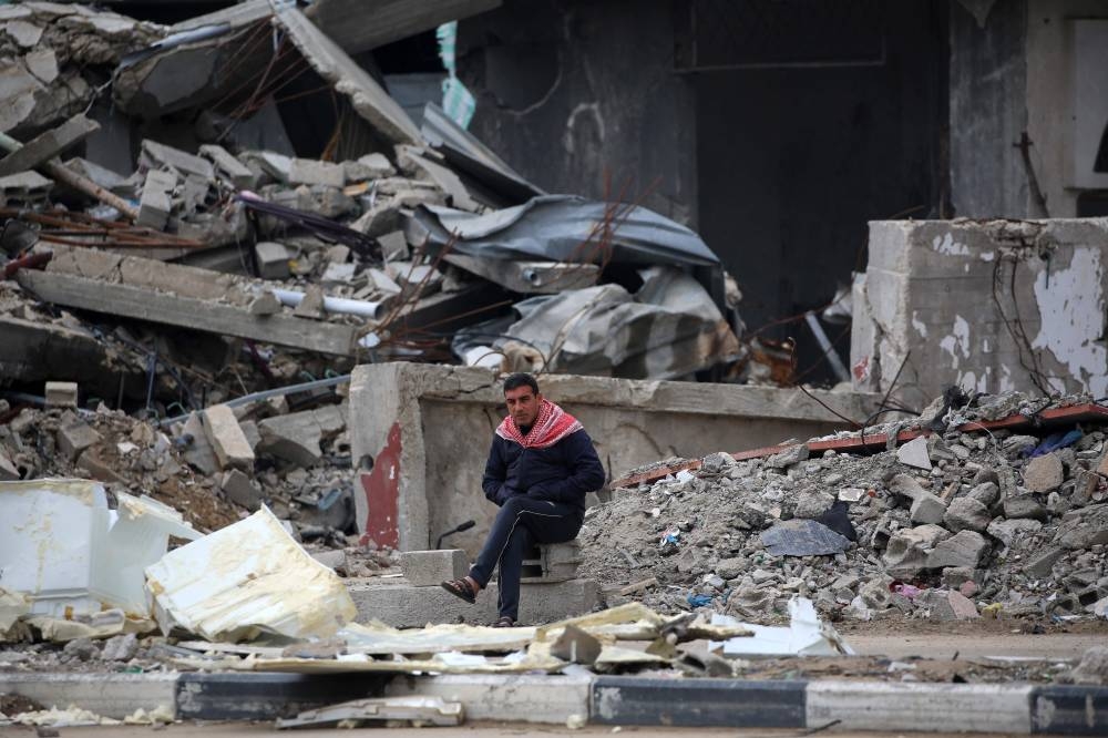 A Palestinian man sits in front of a destroyed building in the war-devastated Bureij refugee camp in the central Gaza Strip Friday.