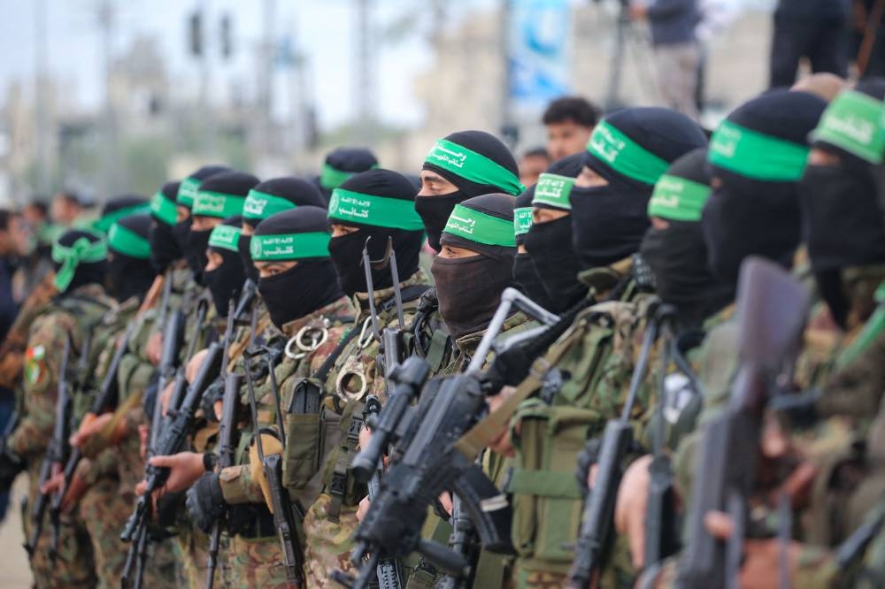 Hamas fighters secure an area before handing over three Israeli hostages to a Red Cross team in Deir el-Balah, central Gaza, on Saturday. AFP