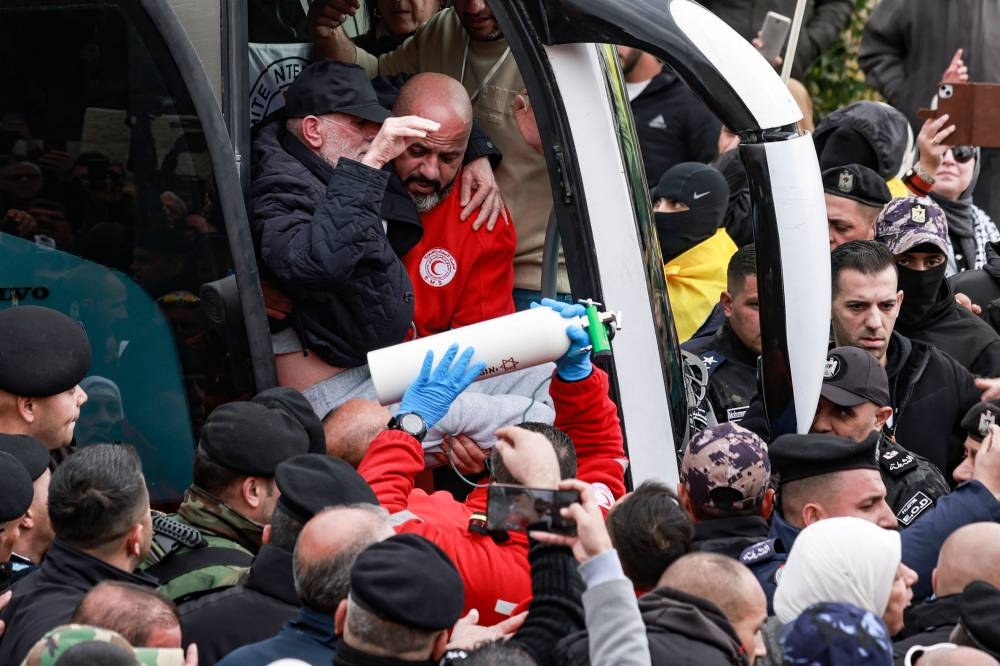 A Palestinian prisoner with health issues, newly released from an Israeli prison, is carried out of a bus by a member of Red Cross as another carries an oxygen canister upon his arrival in the occupied West Bank city of Ramallah, on Saturday. AFP