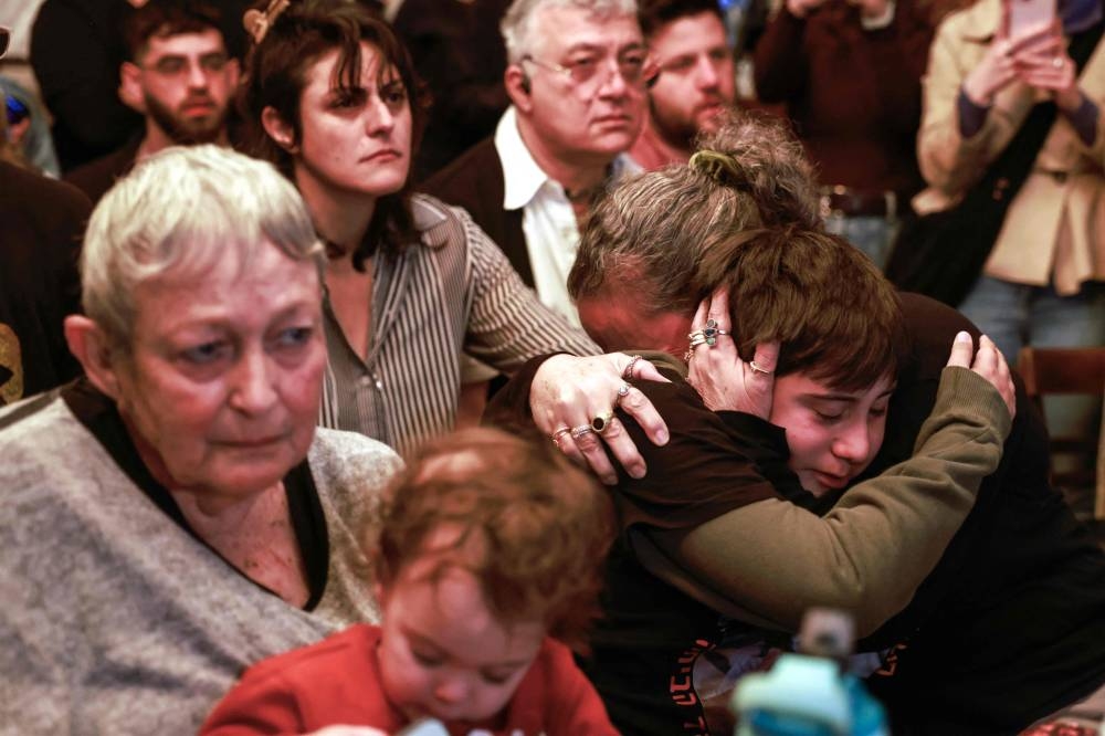 Family members of Israeli hostage Ohad Ben Ami, held captive in the Gaza Strip since the October 7, 2023 attack by Palestinian militants, react as they watch his release together with two other hostages by Hamas on TV on February 8, 2025,  in Tel Aviv. Hamas is set to release three Israeli hostages on February 8 in exchange for 183 prisoners held by Israel in the fifth exchange of a fragile Gaza ceasefire. (Photo by Menahem Kahana / AFP)