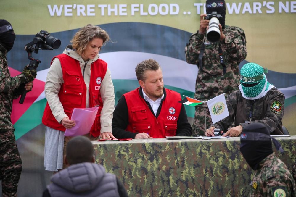 A member of the Red Cross team signs documents before Palestinian Hamas fighters handover three Israeli hostages in Deir el-Balah, central Gaza, on Saturday. AFP