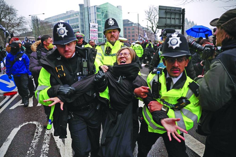 Police officers take away a protester who was attempting to block the road during the protest.