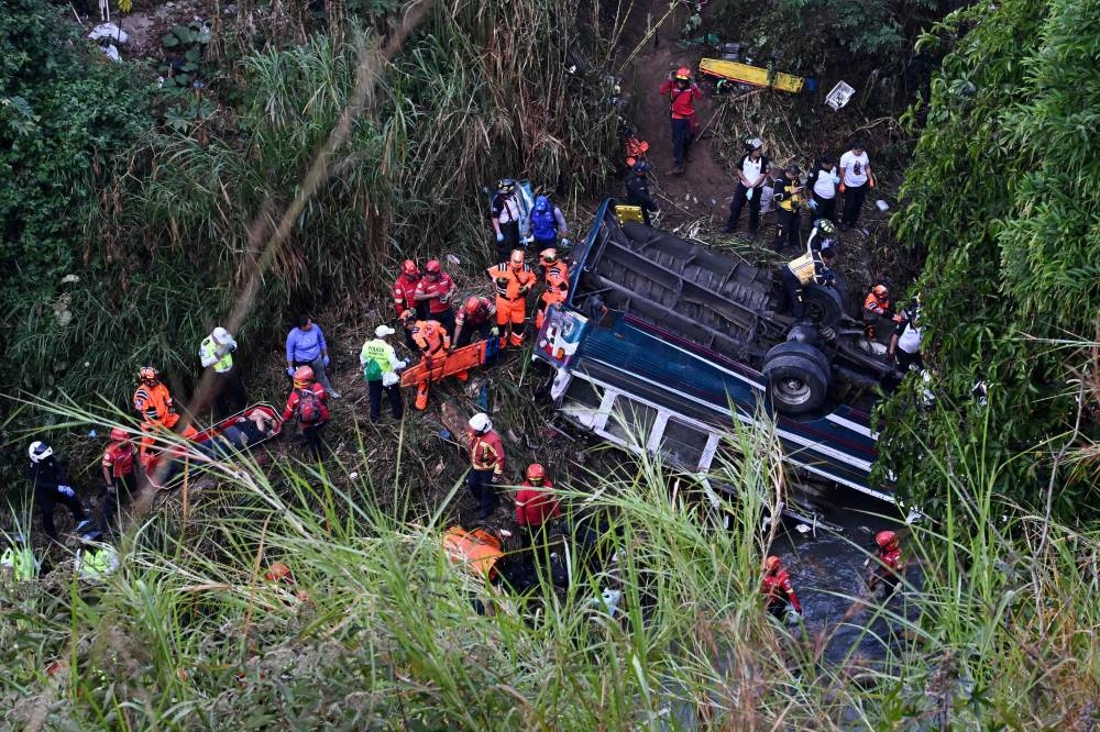 Firefighters work at the scene of an accident in which a bus fell down a ravine in Guatemala City, on Monday. AFP
