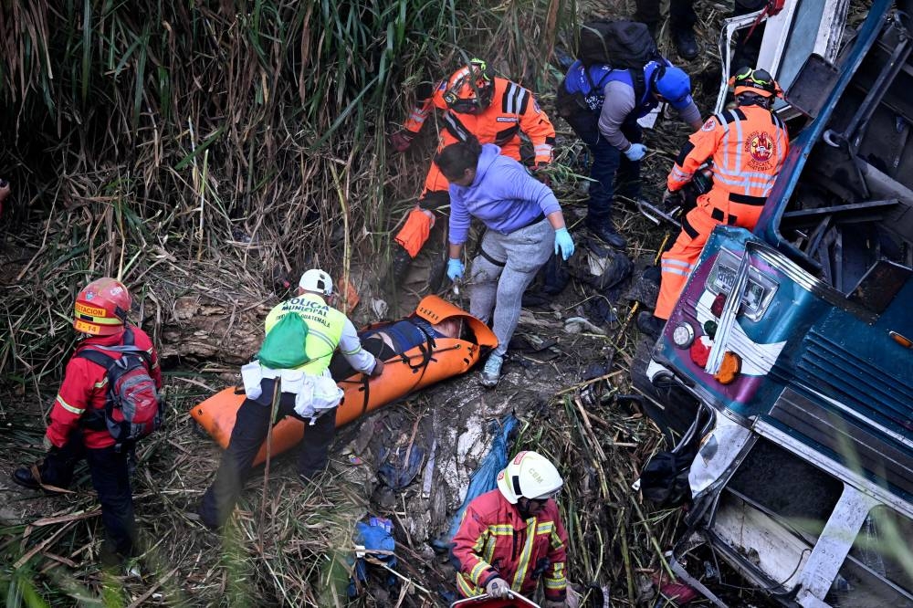 Firefighters and police work at the scene of an accident in which a bus fell down a ravine in Guatemala City, on Monday. REUTERS