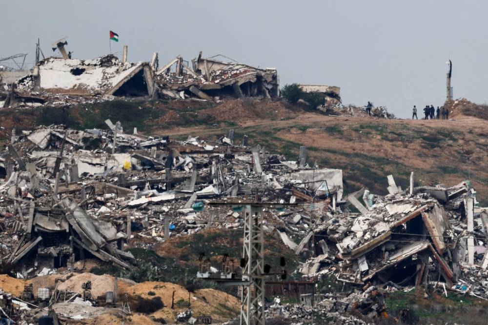 A Palestinian flag flutters as people walk near buildings in ruins in Gaza, as seen from Israel, on Tuesday. REUTERS