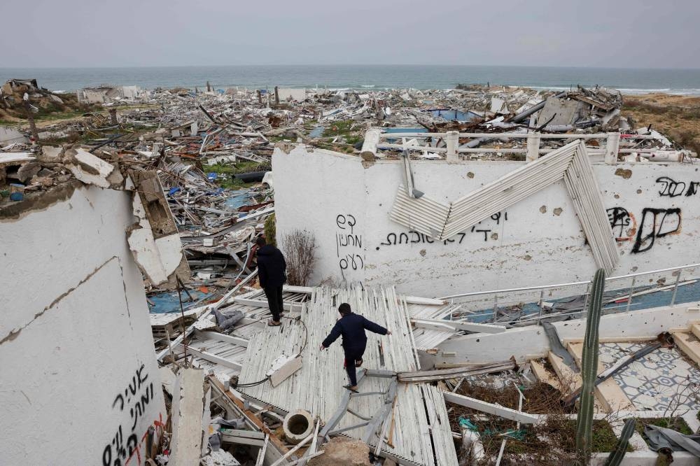 Youths walk amid debris of the destroyed Bianco Resort in western Gaza City, Tuesday. AFP