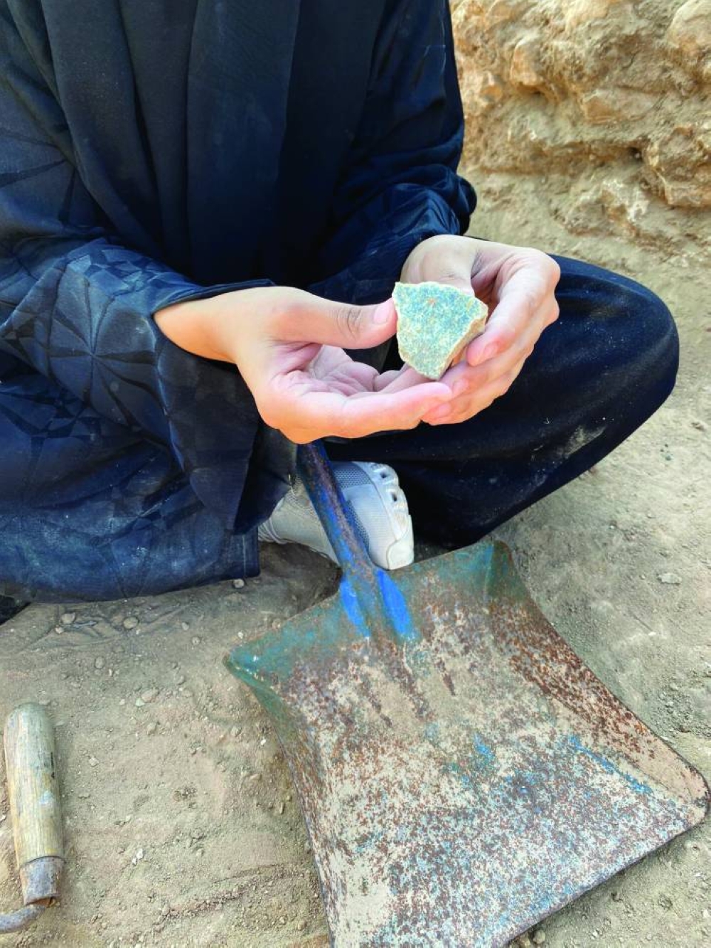 A volunteer shows the pottery shard she found.