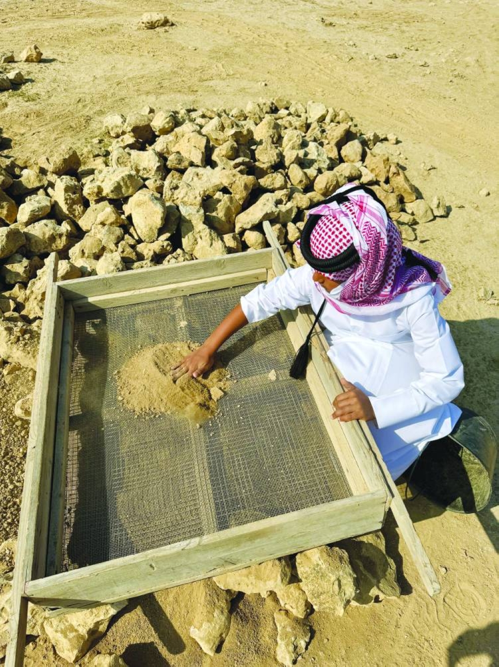 A boy sieves soil for any pottery finds