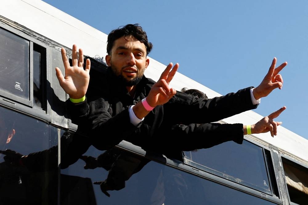 A freed Palestinian prisoner gestures from a bus after being released by Israel as part of a hostages-prisoners swap and a ceasefire deal in Gaza between Hamas and Israel, in Khan Younis, in the southern Gaza Strip, Saturday. REUTERS