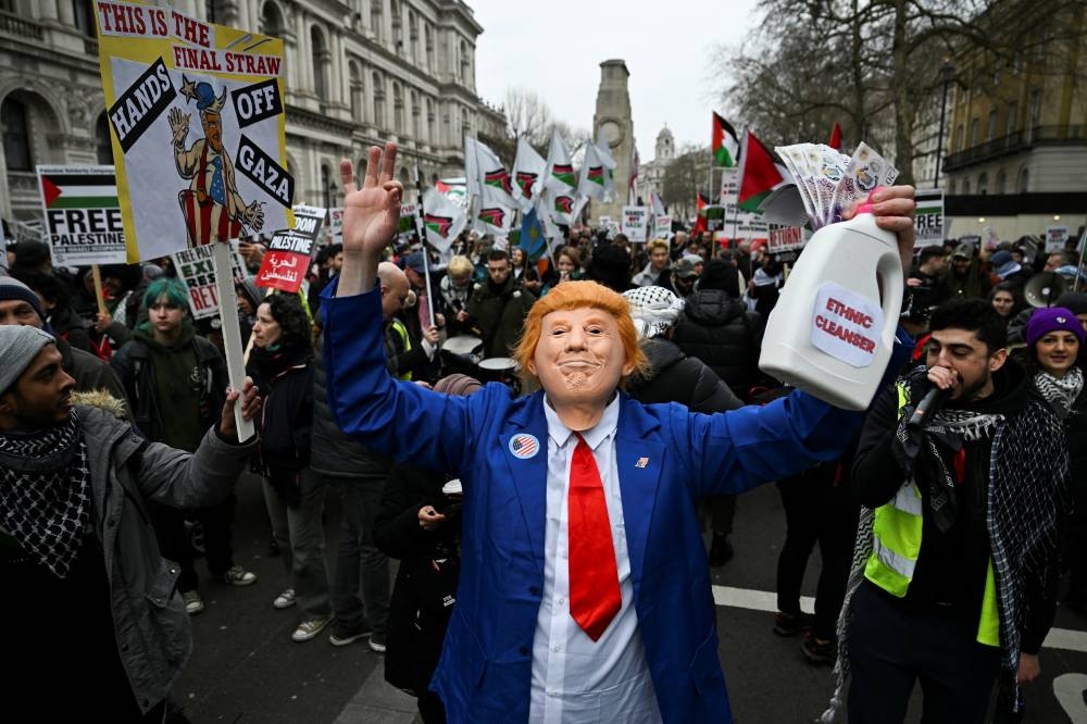 A man wears a mask depicting US President Donald Trump as pro-Palestinian demonstrators attend a march in opposition Trump's plan to displace Palestinians from Gaza and "take over" the territory, in London, on Saturday. REUTERS