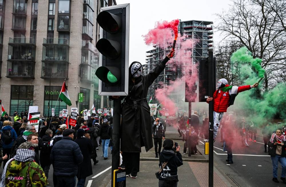 Pro-Palestinian demonstrators hold flares during a march in opposition to US President Donald Trump's plan to displace Palestinians from Gaza and "take over" the territory, in London, on Saturday. REUTERS