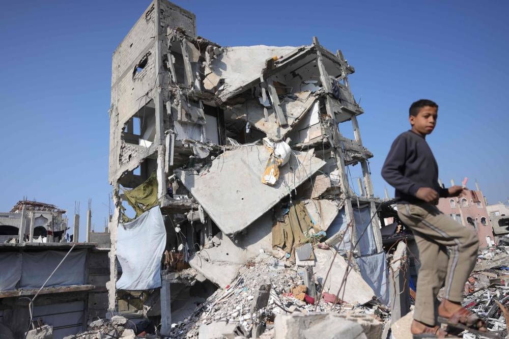 A Palestinian youth walks next to a destroyed building in Jabalia in the northern Gaza Strip, on Monday. AFP