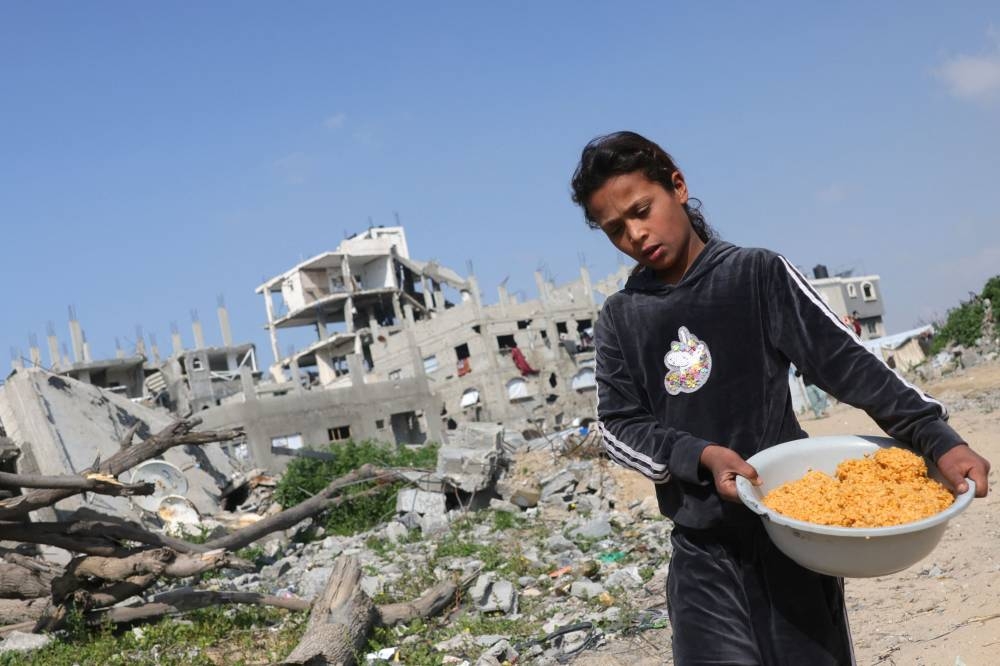 A Palestinian girl carries a food ration back to her family in Jabalia in the northern Gaza Strip, on Monday. AFP