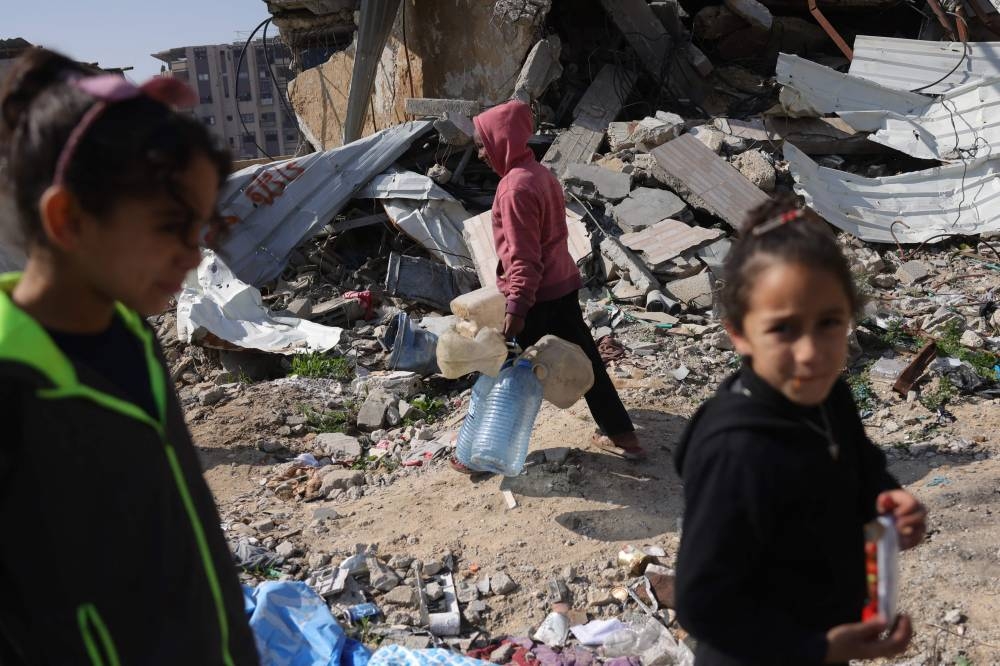 Palestinian children makes their way to refill on drinking water in Jabalia in the northern Gaza Strip, on Monday. AFP