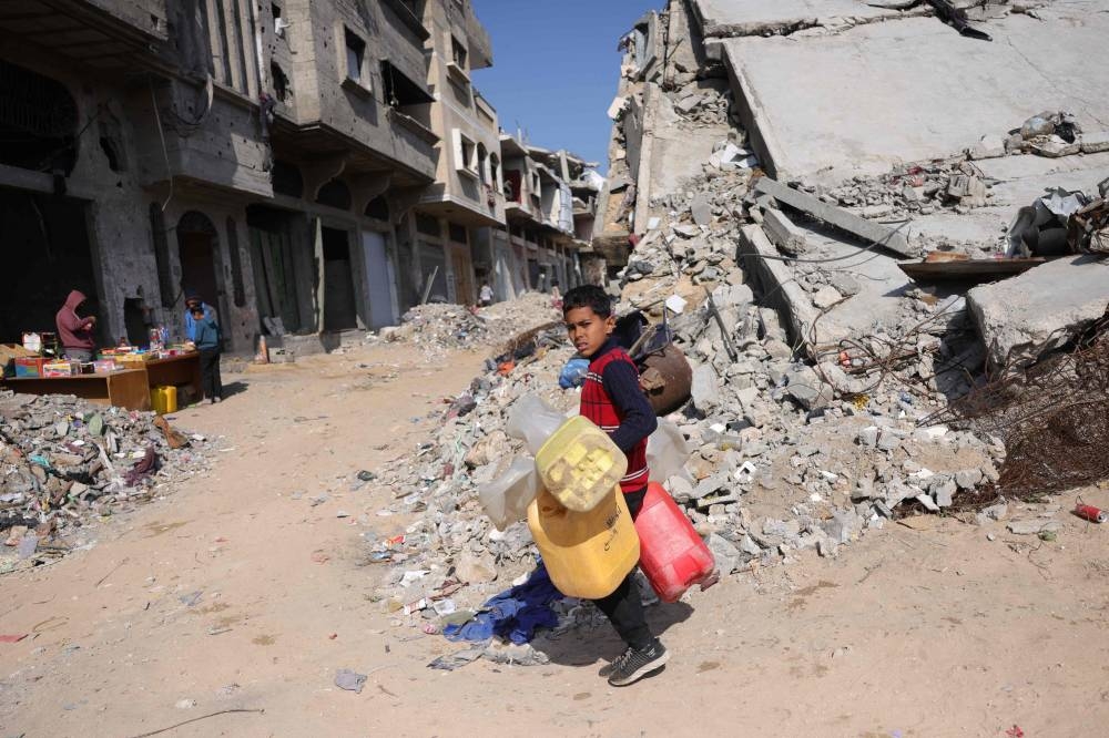 A Palestinian boy makes his way to refill drinking water in Jabalia in the northern Gaza Strip Monday.