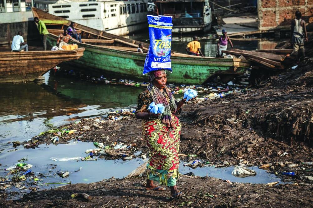 A woman selling detergent walks past pirogues while searching for customers at the shores of Lake Kivu in Bukavu.