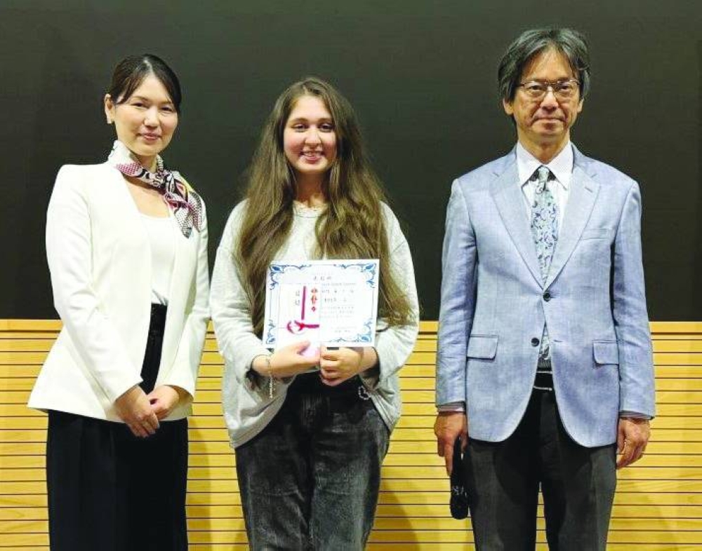 First prize winner Amna Owais is flanked by ambassador Naoto Hisajima and another official.