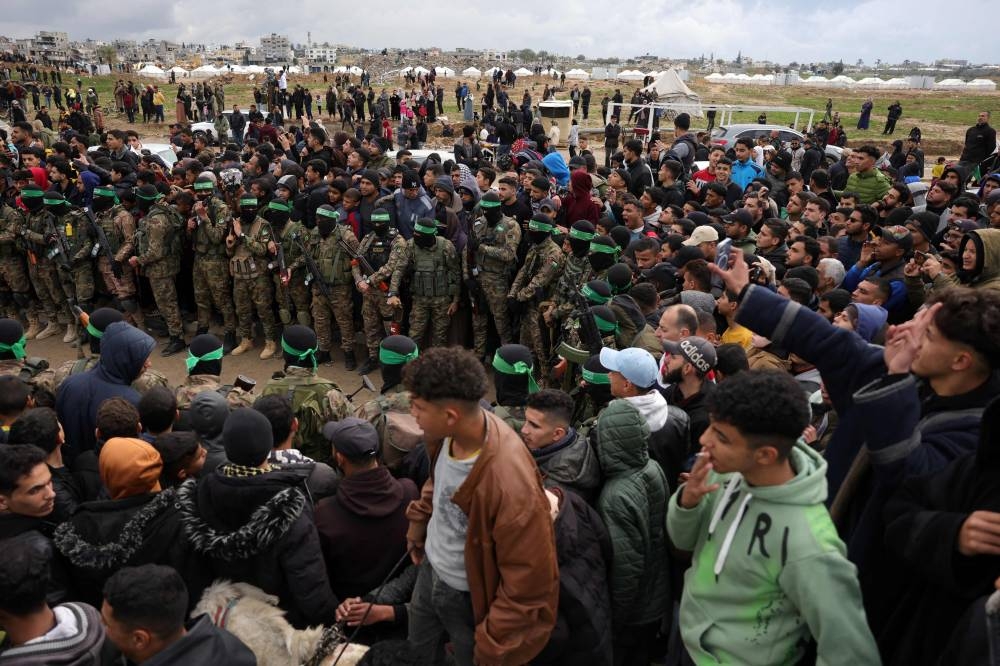 Palestinian Hamas fighters and people gather in Nuseirat in the central Gaza Strip, as preparations take place for the release of three Israeli hostages part of the seventh hostage-prisoner swap, on Saturday. AFP