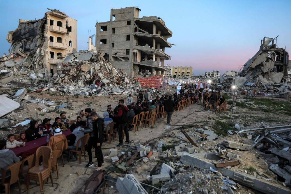 People gather by the rubble of destroyed buildings for a mass gathering for a communal iftar fast-breaking meal on the second day of the Muslim holy month of Ramadan in the area of al-Dahduh in Gaza City's Tal al-Hawa district on Sunday. AFP