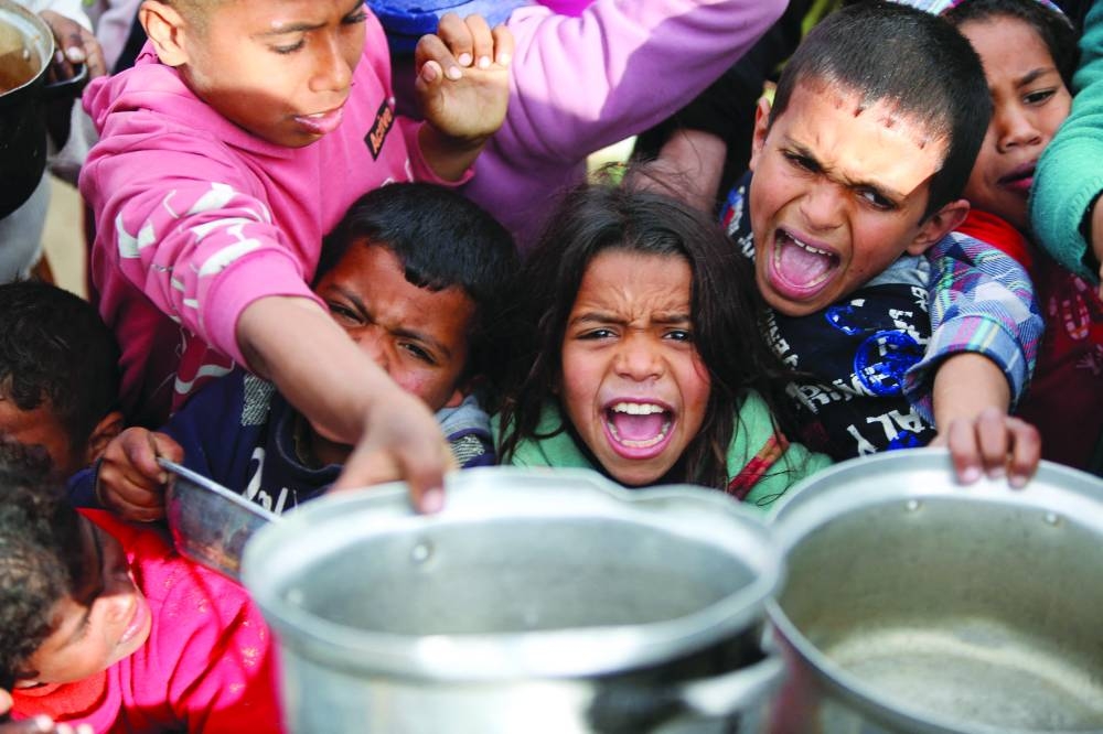 Palestinian children gather to receive food cooked by a charity kitchen, in Khan Younis, in the southern Gaza Strip, Monday.