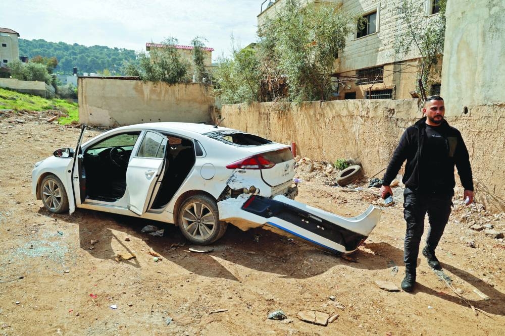 
A Palestinian man walks next to a damaged car during an Israeli raid in Jenin, in the occupied West
Bank, yesterday. 