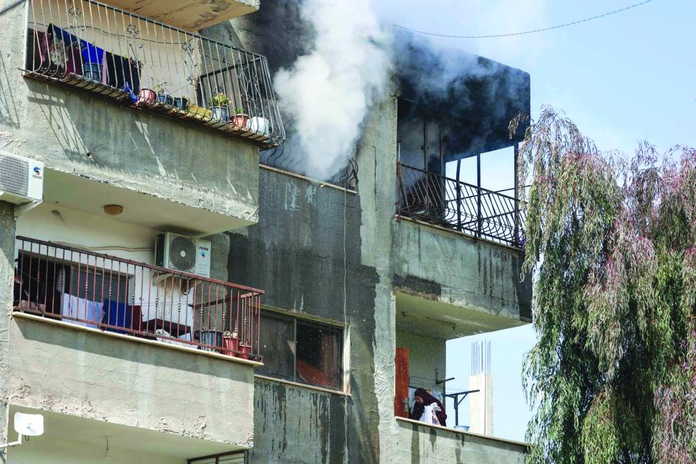 
A Palestinian woman handles laundry on her balcony as smoke billows from an apartment targeted in an Israeli raid in the eastern neighbourhood of Jenin amid a weeks-long offensive in the occupied West Bank, yesterday. 