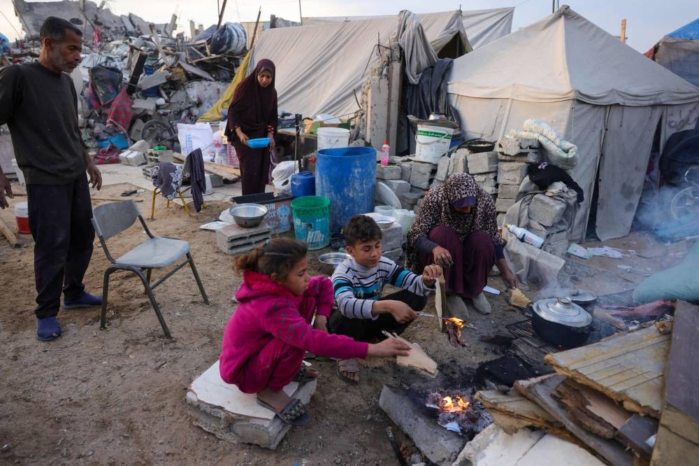 Doctor Khaled Mohammed Abu Jari, 57, (L) head of the critical care department at the Beit Hanoun Hospital, looks on as members of his family prepare a fast-breaking iftar meal outside their tent in Beit Lahia in the northern Gaza Strip during the Muslim holy fasting month of Ramadan. AFP