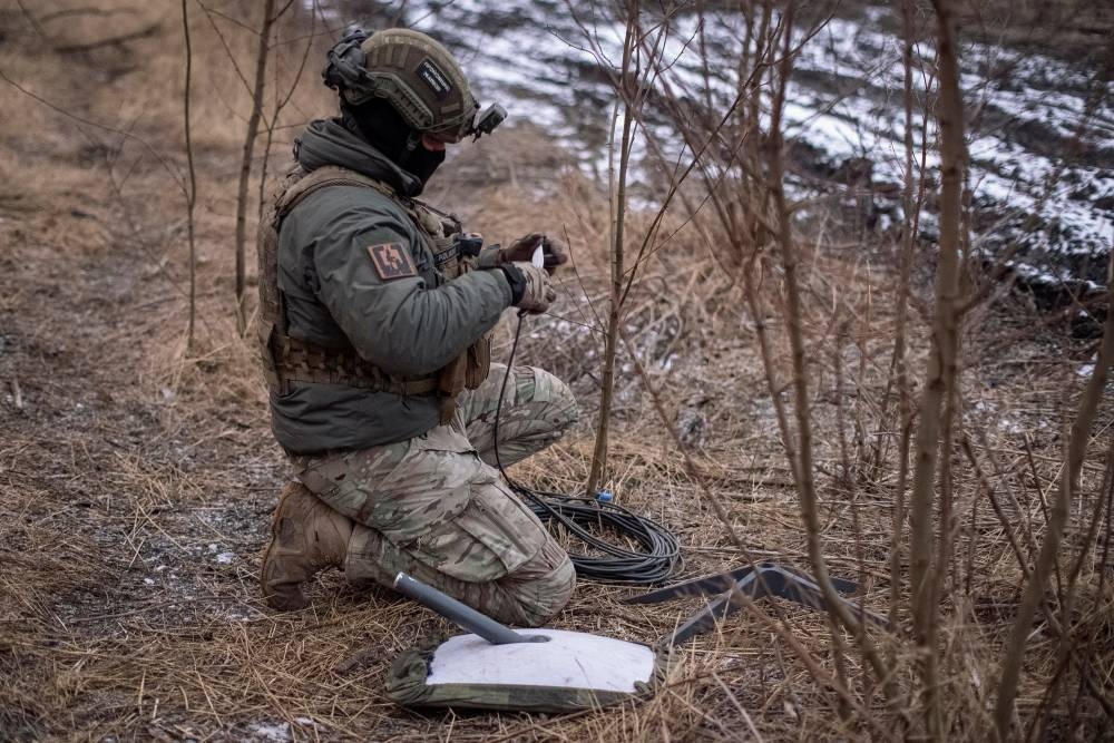 A Ukrainian serviceman prepares a Starlink satellite internet systems at his positions at a front line