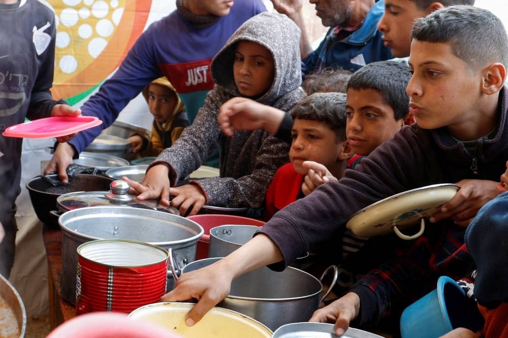 Palestinian children wait to receive food cooked by a charity kitchen, during the holy month of Ramadan, in Khan Younis, in the southern Gaza Strip, on Sunday. REUTERS