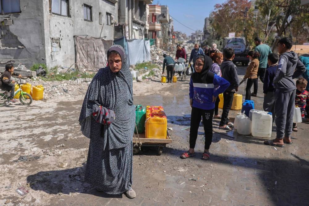 Palestinians queue for water next to a distribution truck at a displacement camp west of Jabalia city in the northern Gaza Strip, on Tuesday. AFP