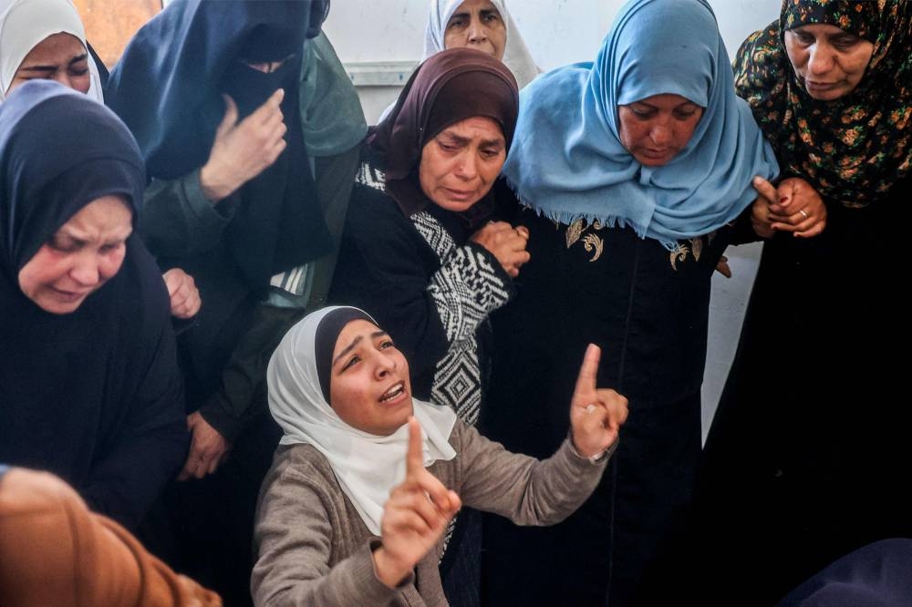 Women mourn by the body of one of the victims who were killed in overnight Israeli bombardment in the north of the Bureij camp for Palestinian refugees, during the funeral in the camp in the central Gaza Strip, on Tuesday. AFP