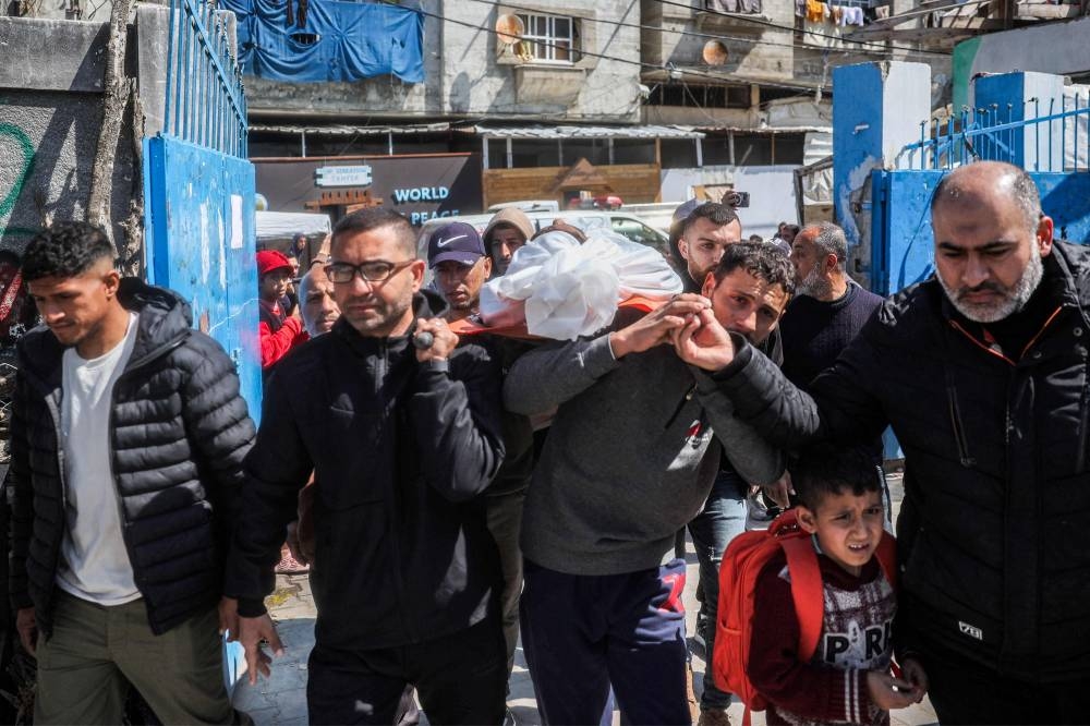 Mourners carry one of the bodies of victims who were killed in overnight Israeli bombardment in the north of the Bureij camp for Palestinian refugees, during the funeral in the camp in the central Gaza Strip, on Tuesday. AFP