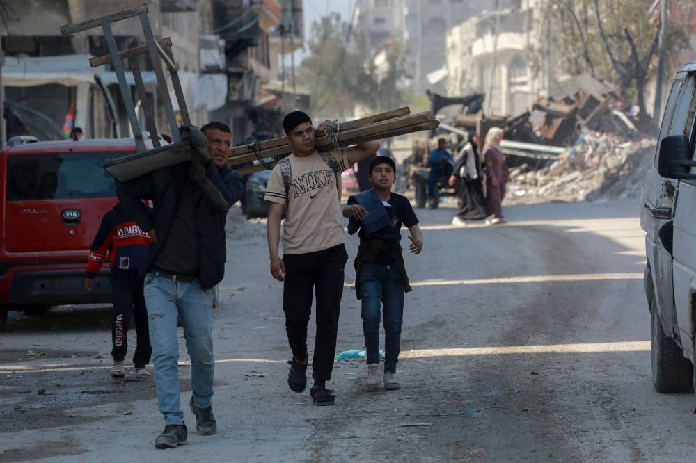 Palestinians carry reclaimed materials as they walk by building rubble west of Jabalia city in the northern Gaza Strip, on Tuesday. AFP