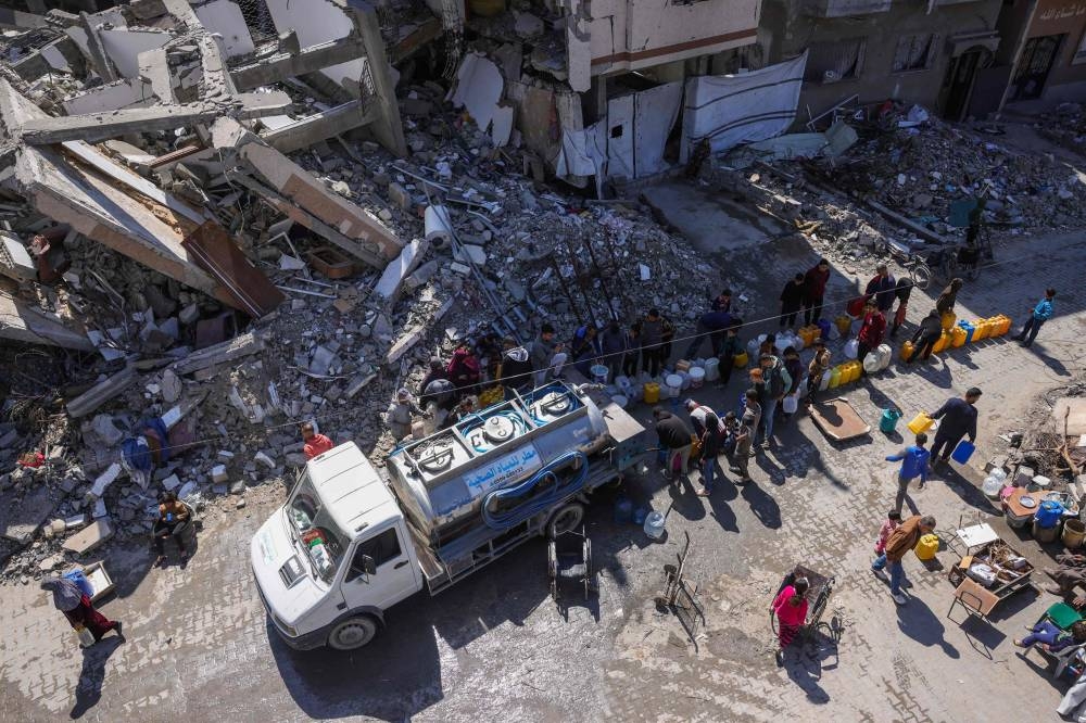 Palestinians queue for water next to a distribution truck at a displacement camp west of Jabalia city in the northern Gaza Strip, on Tuesday. AFP