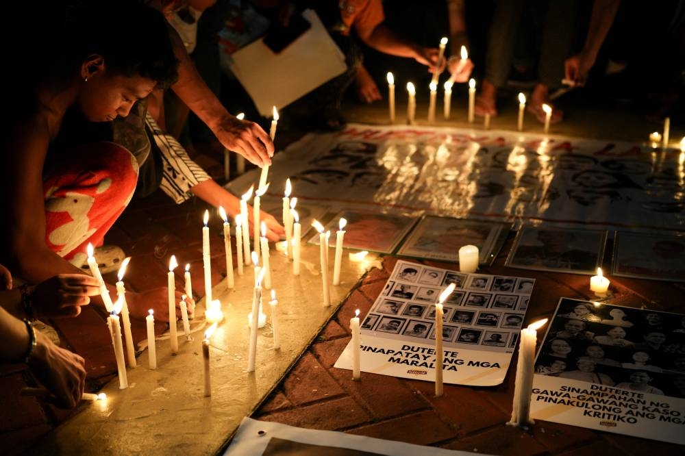 Filipino activists light candles during a protest vigil supporting former President Rodrigo Duterte's arrest warrant by the International Criminal Court, in Quezon City, Metro Manila, on Tuesday. REUTERS