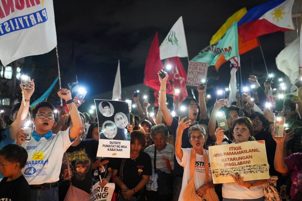Filipino activists raise their phones with flashlight during a protest vigil supporting former President Rodrigo Duterte's arrest warrant by the International Criminal Court, in Quezon City, Metro Manila, on Tuesday. REUTERS