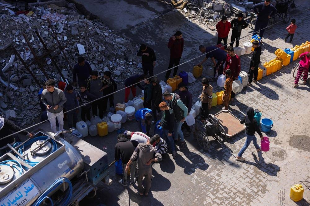 Palestinians queue for water at a camp west of Jabalia city in the northern Gaza Strip Tuesday.