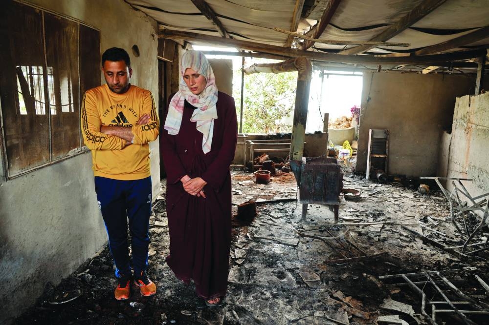 Palestinians stand in a damaged building, following an Israeli settlers' attack, near Duma in Nablus, in the occupied West Bank, yesterday.