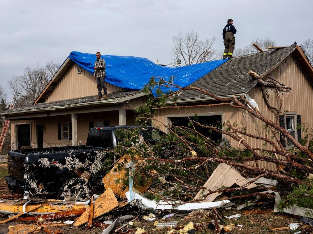 People help cover a damaged roof on Saturday in Poplar Bluff, Missouri. Many homes throughout Harmony Hills were damaged by the severe weather on Friday night that left one person dead in Butler County, Missouri. AFP